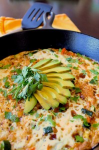 egg white frittata in a black skillet topped with fresh herbs and avocado 