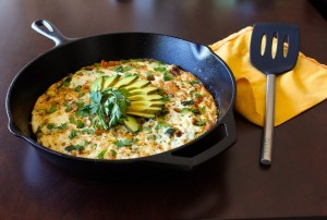 egg white frittata topped with avocado slices in a black skillet 