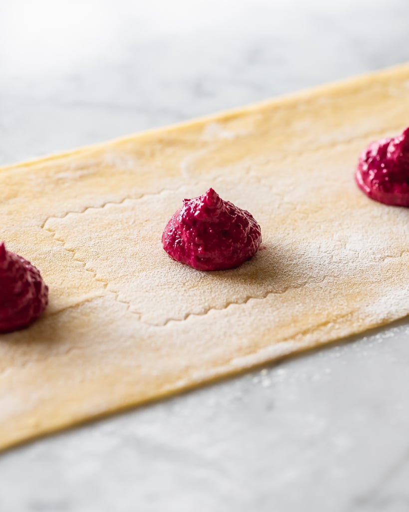 a sheet of pasta dough topped with dollops of beet filling