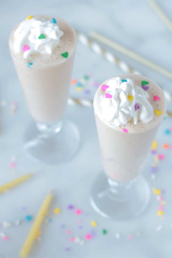Vegan Birthday Cake Protein Shake in two high glasses topped with rainbow sprinkles