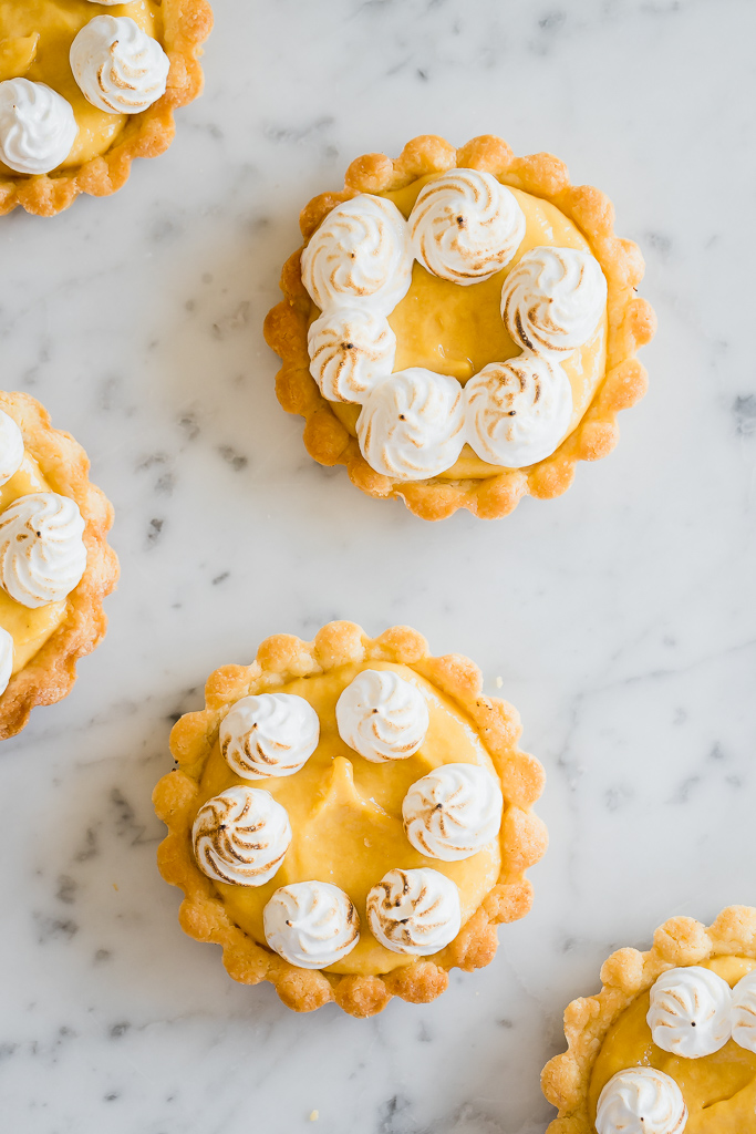 overhead shot of mango curd mini tartlets on a marble countertop 