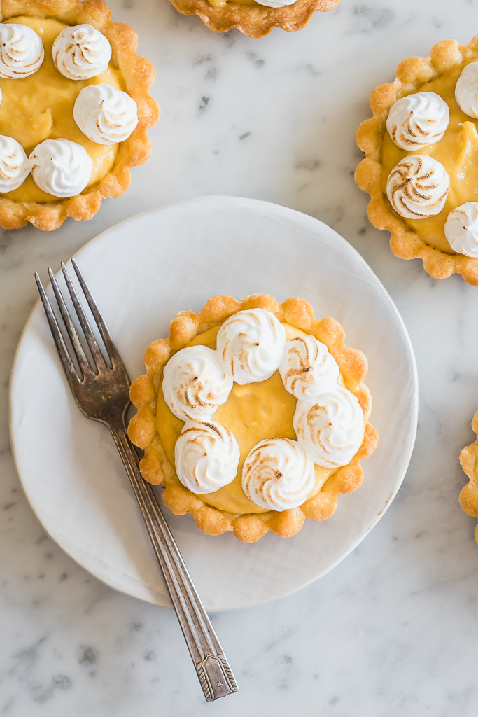 a homemade mango curd tart on a small plate with a fork on the side