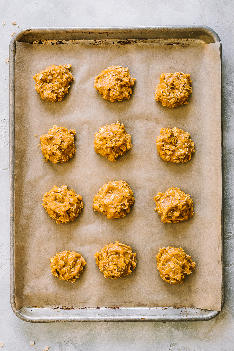 unbaked pumpkin oatmeal cookie dough balls on a lined baking sheet