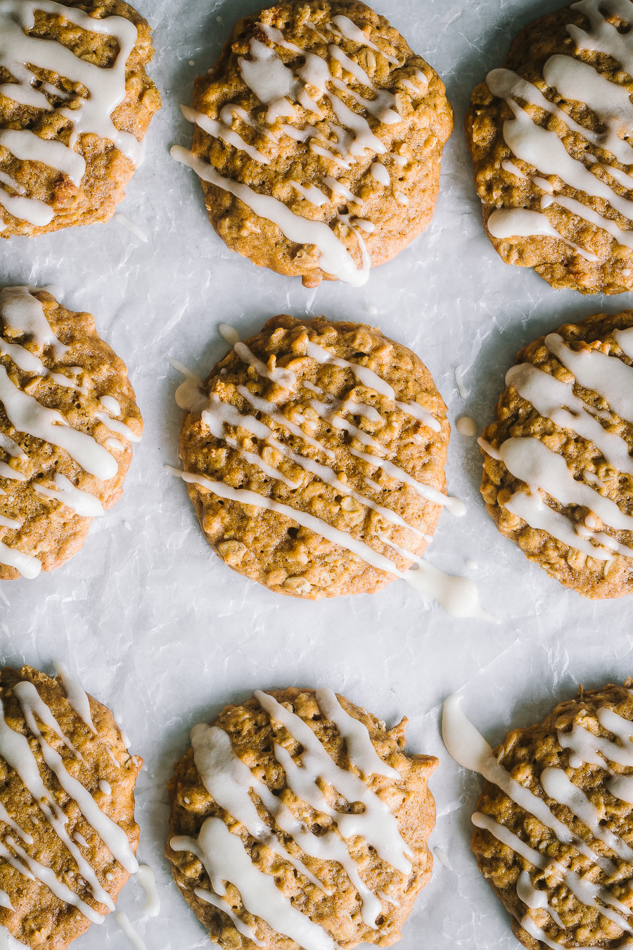 overhead shot of freshly maple glazed pumpkin oatmeal cookies on parchment paper