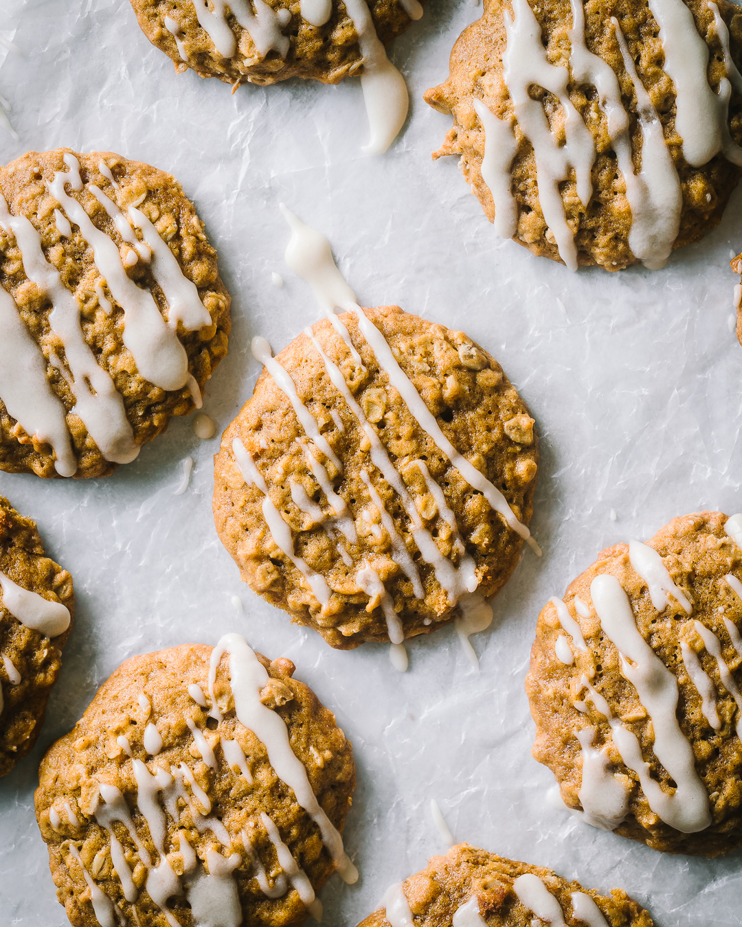 overhead shot of homemade healthy pumpkin oatmeal cookies with maple glaze on parchment paper