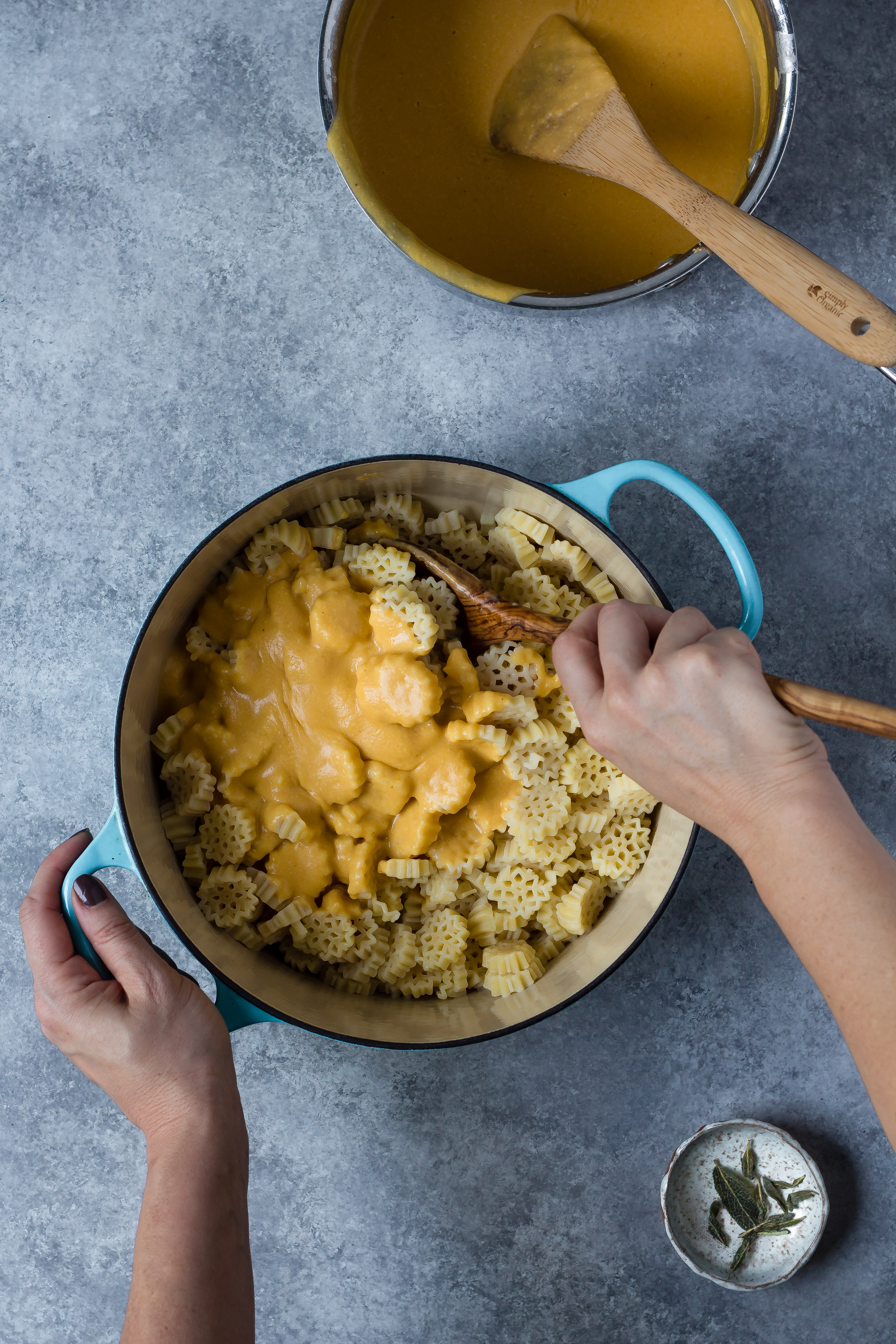 mixing vegan butternut squash cheese sauce with pasta in a pot