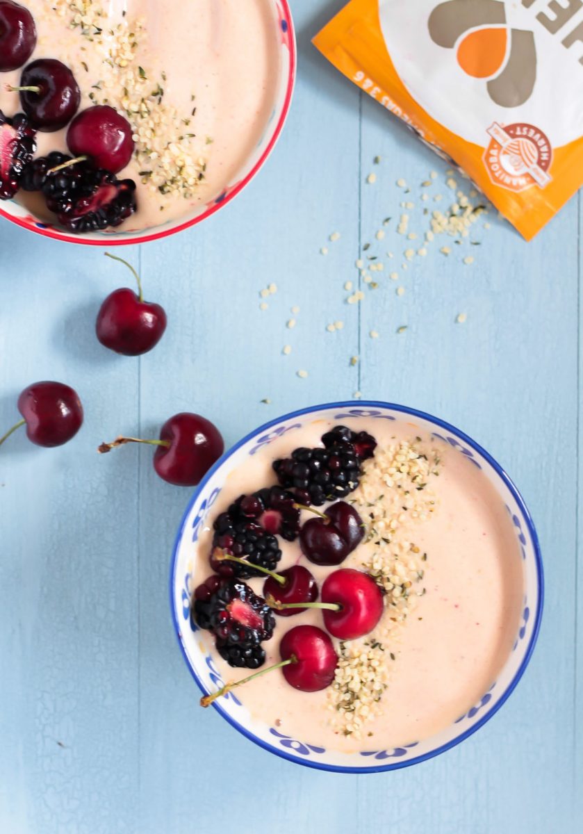 overhead shot of two peanut butter and jelly smoothie bowls topped with fresh cherries and hemp seeds