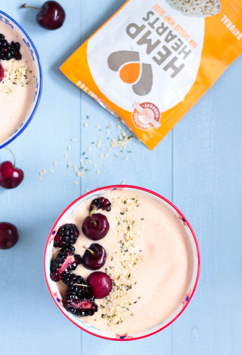 Peanut Butter & Jelly Smoothie Bowl with help seeds, blackberries and cherries on a pale blue wooden surface