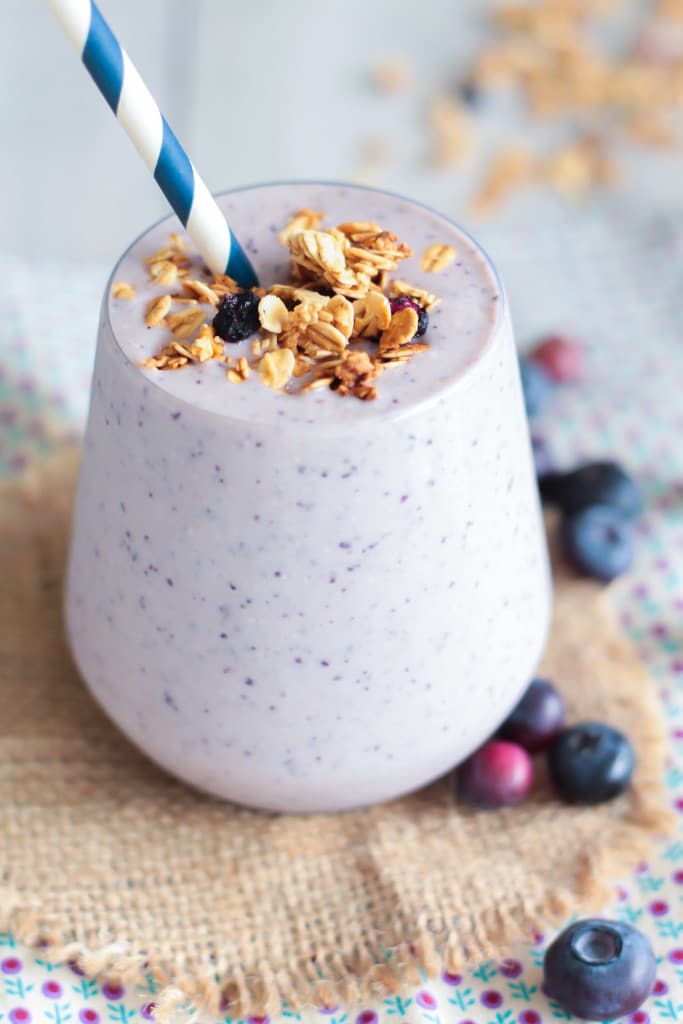 side view of a glass of Blueberry Crisp Smoothie with collagen peptides topped with granola