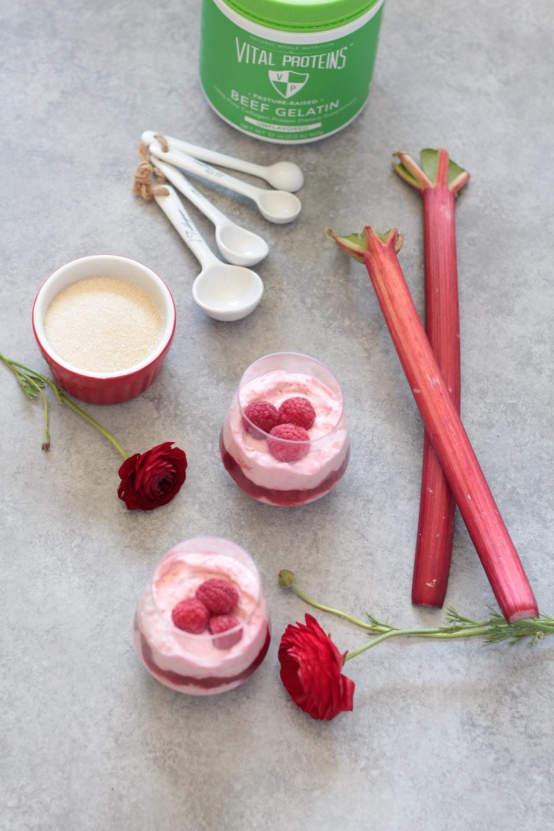 two Raspberry Rhubarb Mousse Parfaits next to a bowl with gelatine and some rhubarb stalks