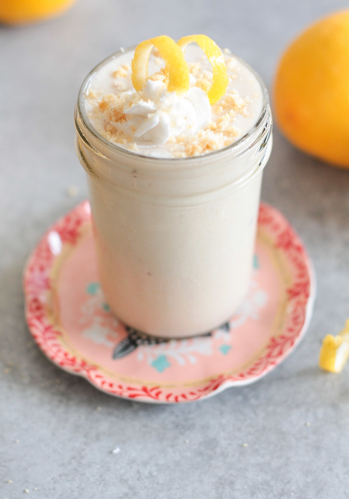 side view of a glass of Lemon Cream Pie Protein Shake topped with lemon zest and a swirl of cream