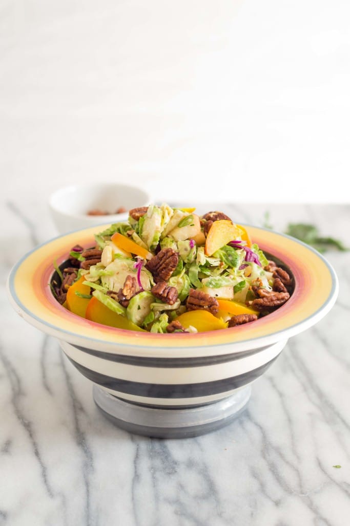 side view of Autumn Brussels Sprout Slaw with cabbage, pecans and apples on a marble countertop