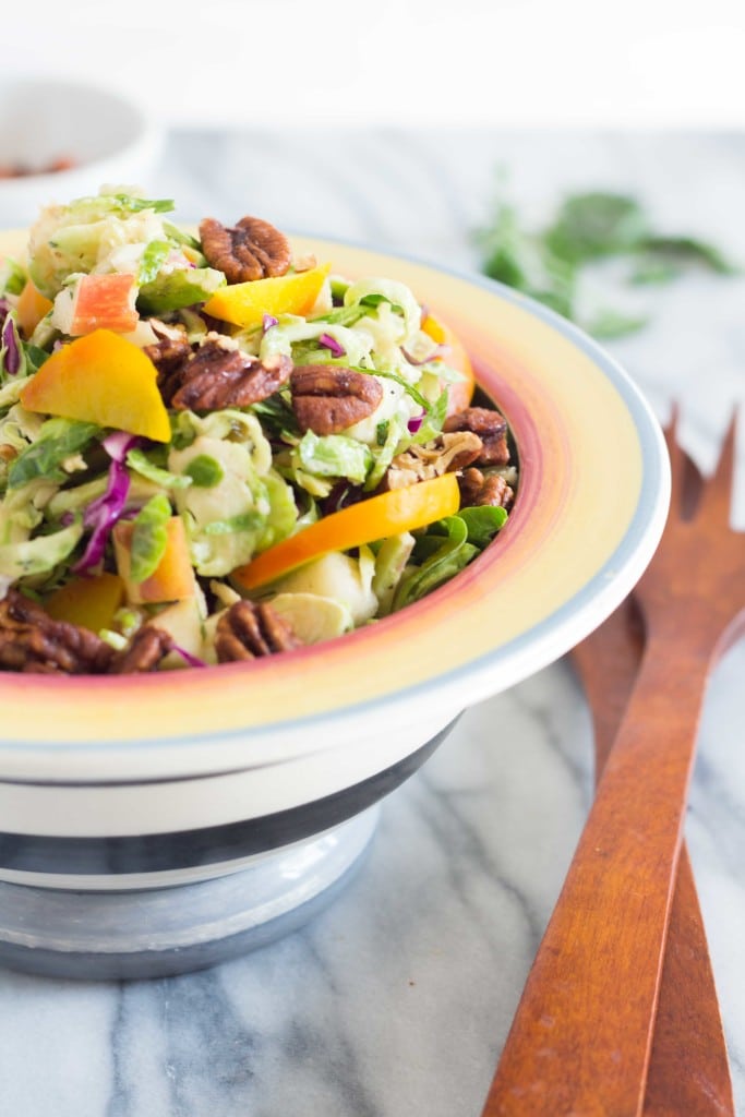 Autumn Brussels Sprout Slaw with apples, raisins and pecans in a striped salad bowl 