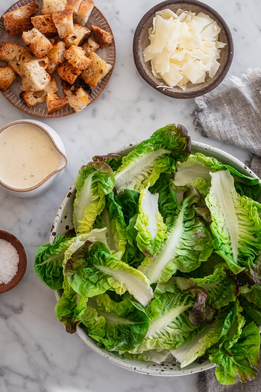 A bowl of lettuce, croutons, Parmesan and Caesar dressing