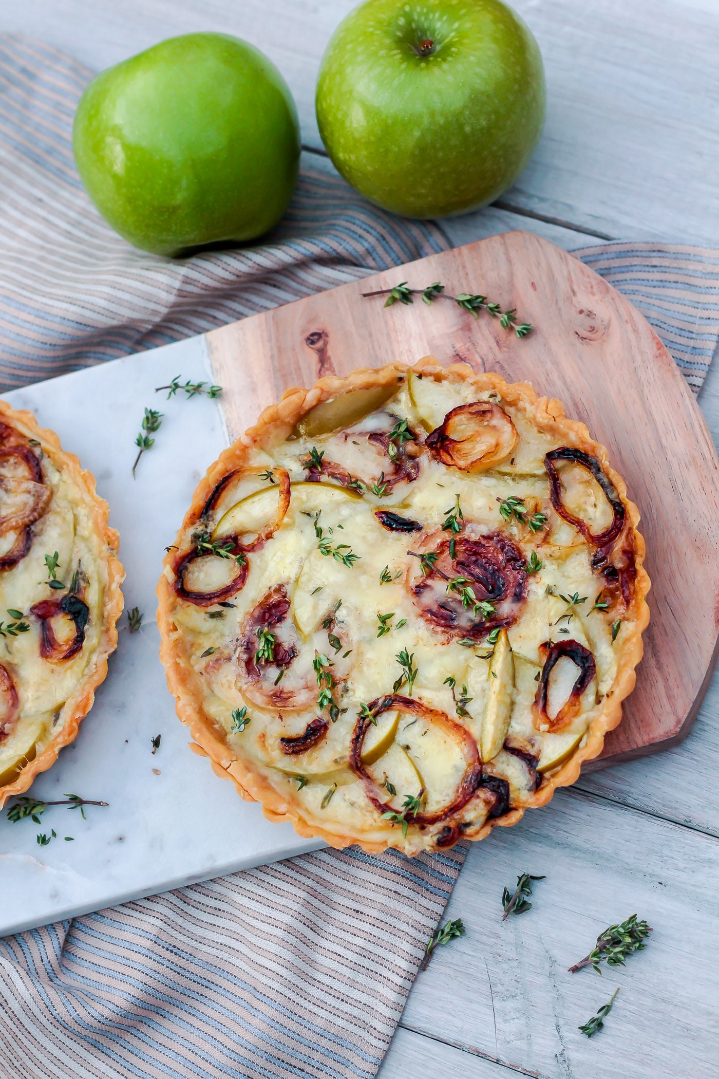 overhead shot of two small Savory Apple Tarts with caramelized onions, fresh thyme and gruyere 