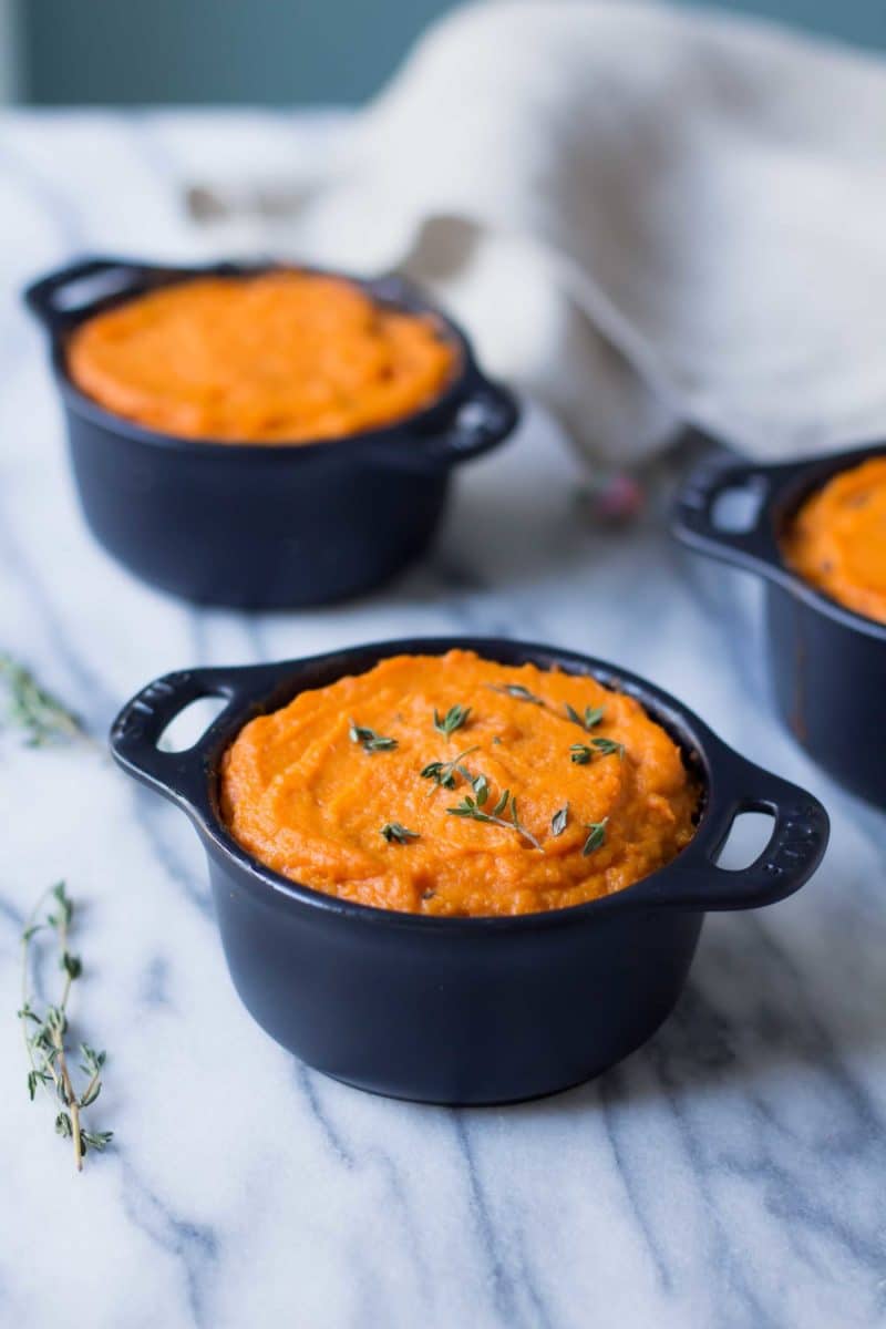 vegetarian shepherd's pie with lentils and sweet potato topping served in individual black casseroles on a marble counter top