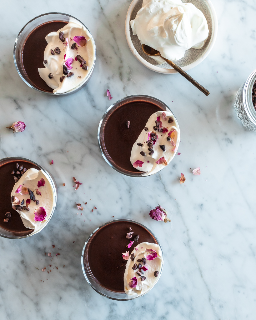 overhead shot of bourbon chocolate pots de creme with coconut whipped cream and rose petals 
