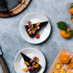 slices of dark chocolate tart with sugared cranberry and satsumas