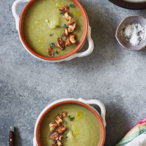 Two bowls of artichoke soup with parsnip chips