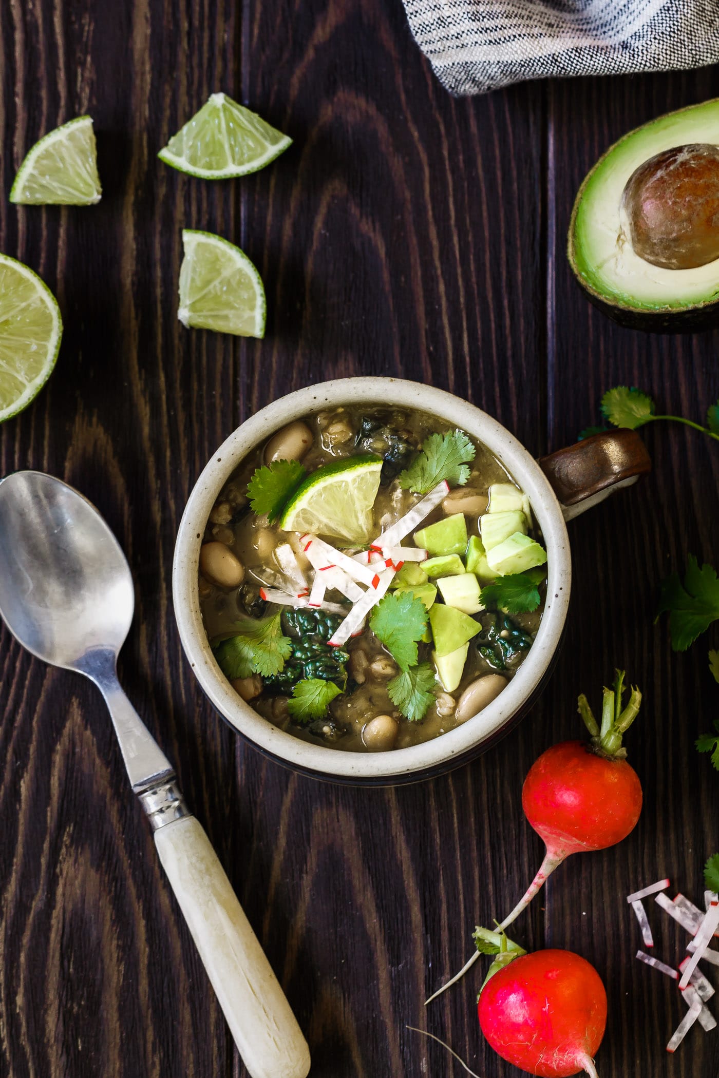 A mug of Farro and White Bean Posole Verde with toppings