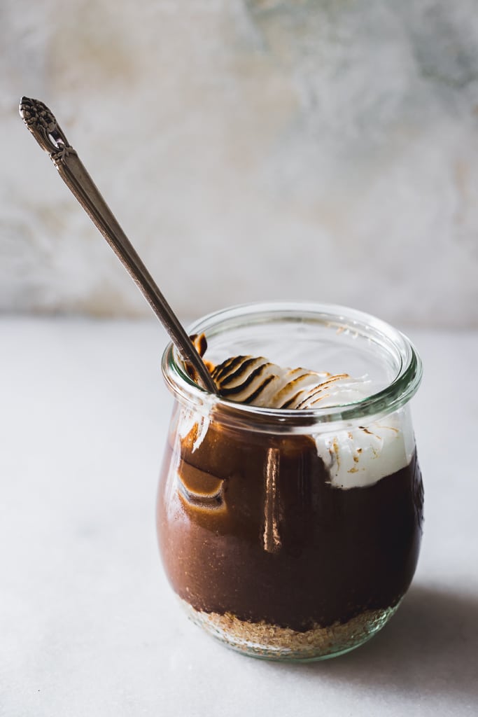 a spoon being dipped into a homemade dairy-free S'mores Parfait in a small glass jar