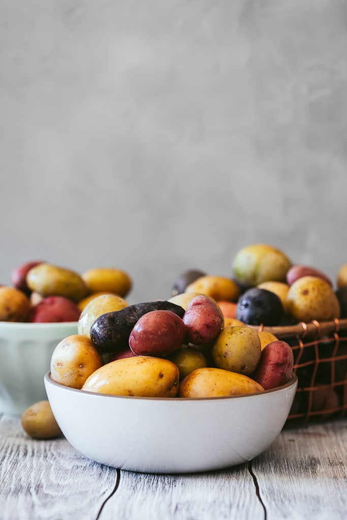 several small bowls filled with multicolored baby potatoes