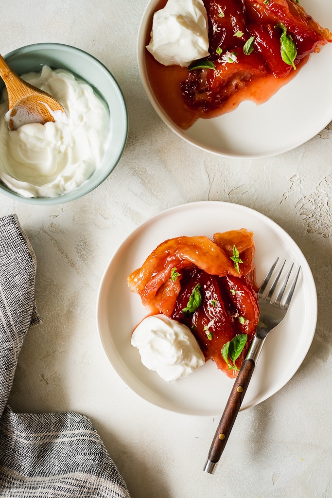 two slices of homemade plum and basil tarte tatin served with whipped cream 