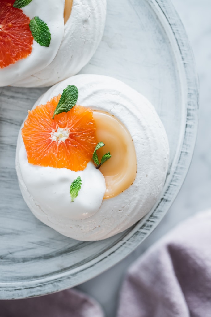 overhead shot of a Vegan Pavlova filled with grapefruit curd and decorated with fresh orange fillet and mint