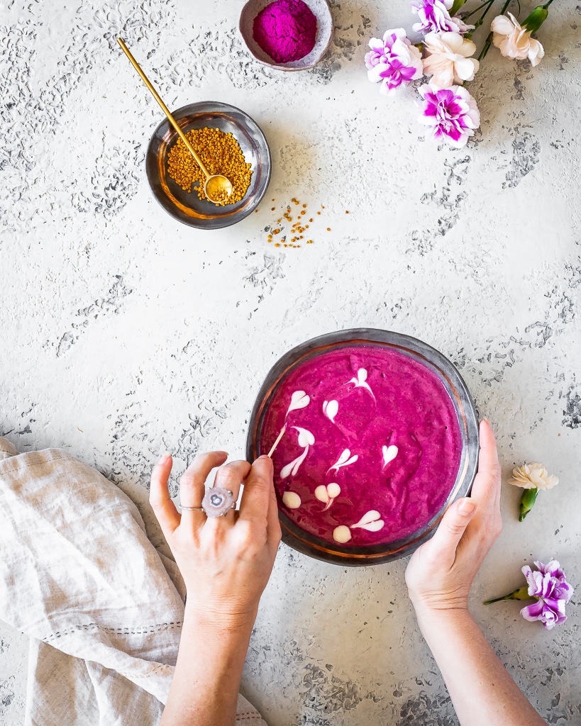 swirling yogurt into a pink dragon fruit smoothie bowl