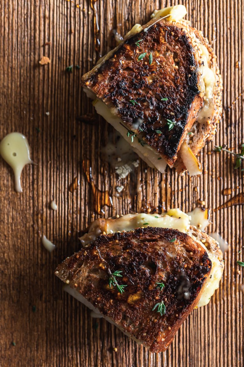 A brie and pear grilled cheese sandwich cut in half and drizzled with honey