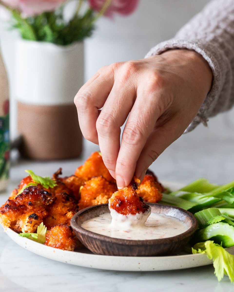 crispy cauliflower appetizer being dipped into ranch dressing