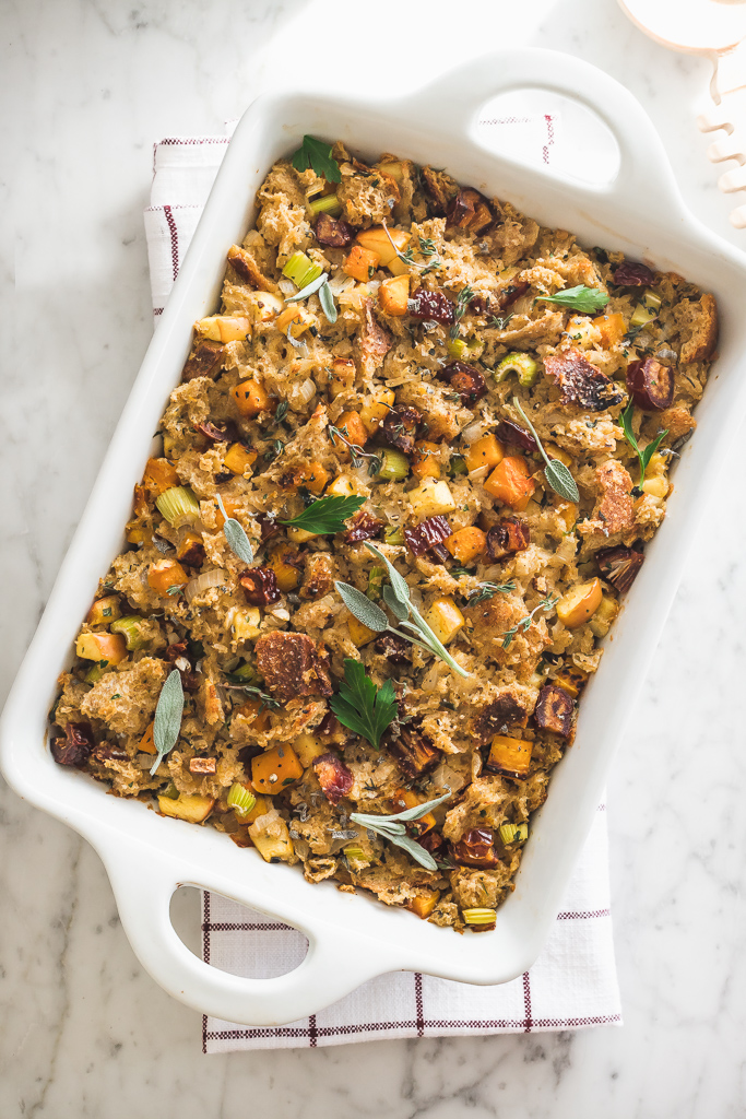 date and apple butternut squash stuffing in a white casserole dish on a marble table