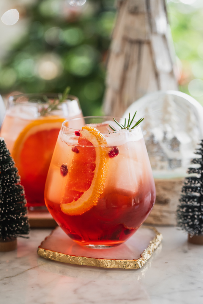 Winter aperol spritz cocktails served in stemless wine glasses with a grapefruit wedge and rosemary sprig