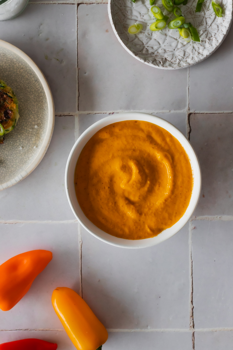 creamy roasted sweet pepper sauce in a white bowl on a grey tile surface