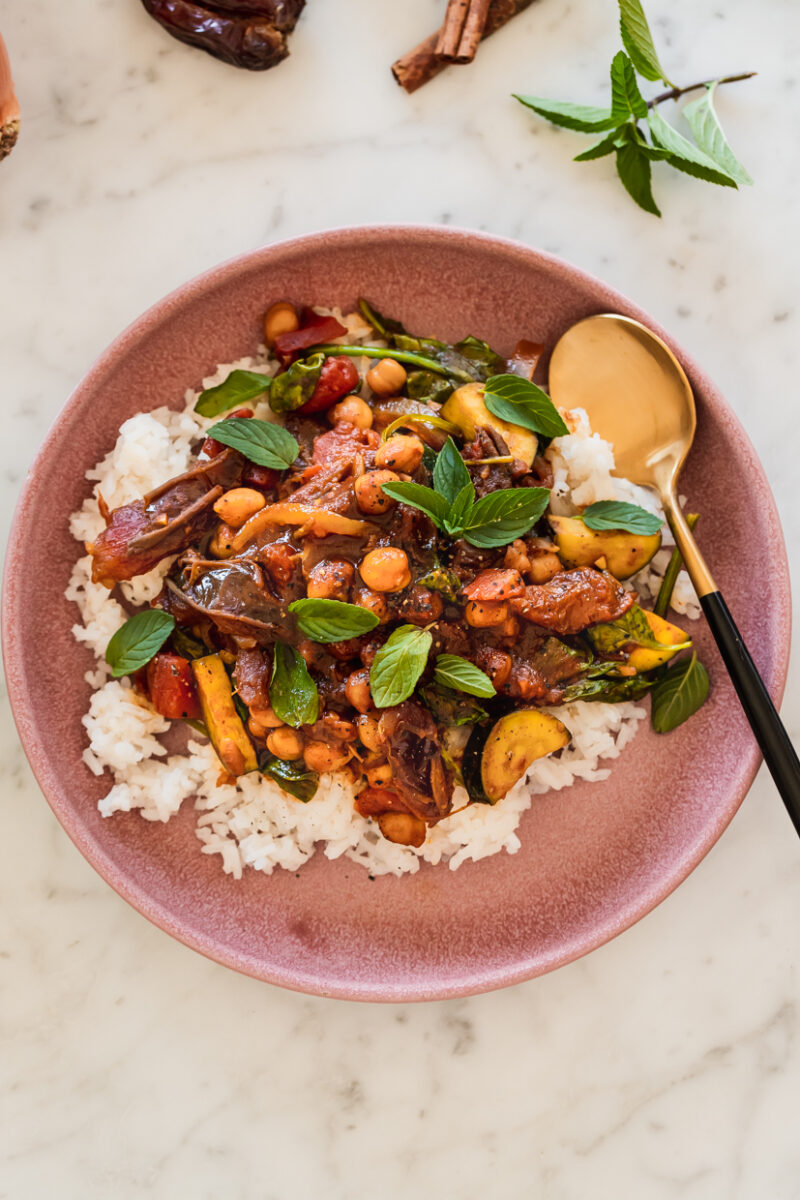 chickpea and date tagine with fresh mint served over rice in a pink dish