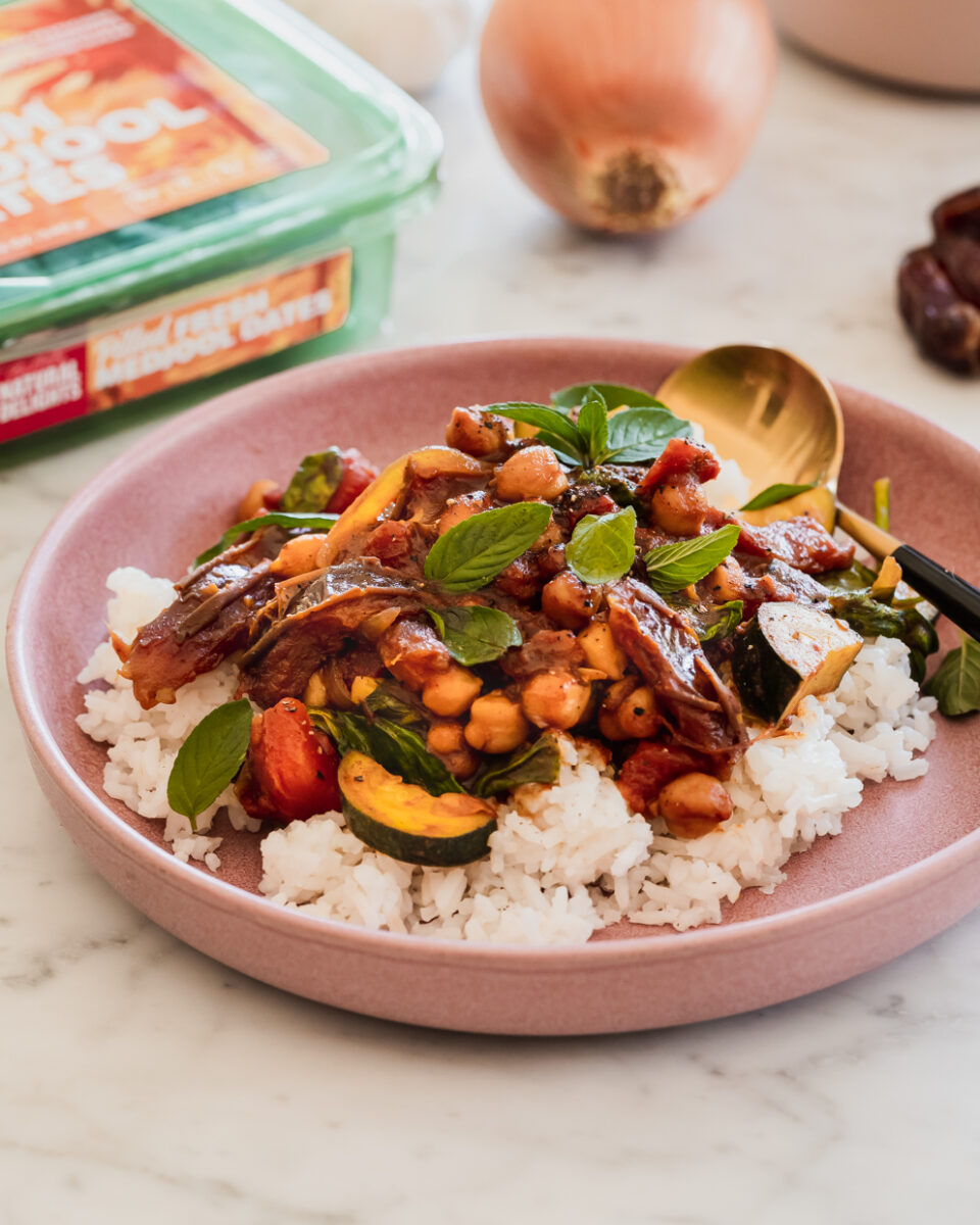 chickpea and date tagine and rice in a shallow pink bowl on a marble table