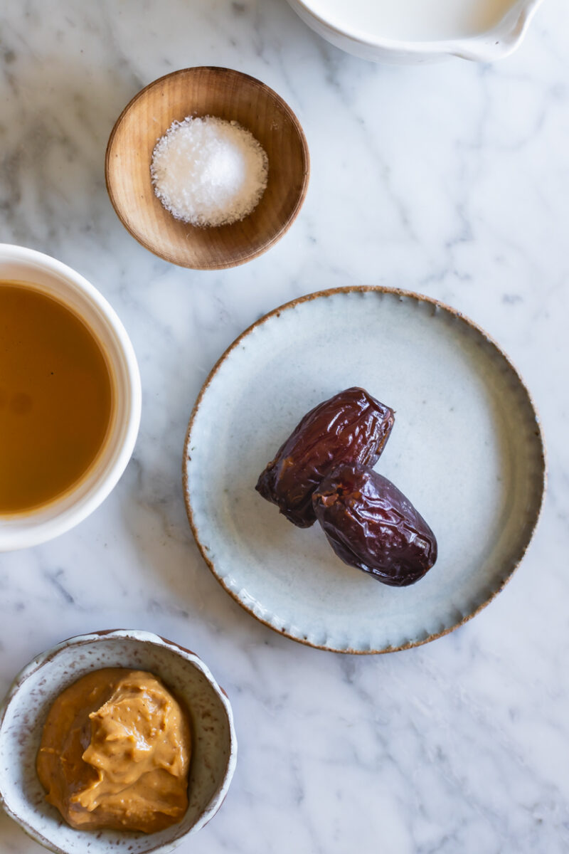 dates, salt, almond butter and espresso in small bowls on a marble table