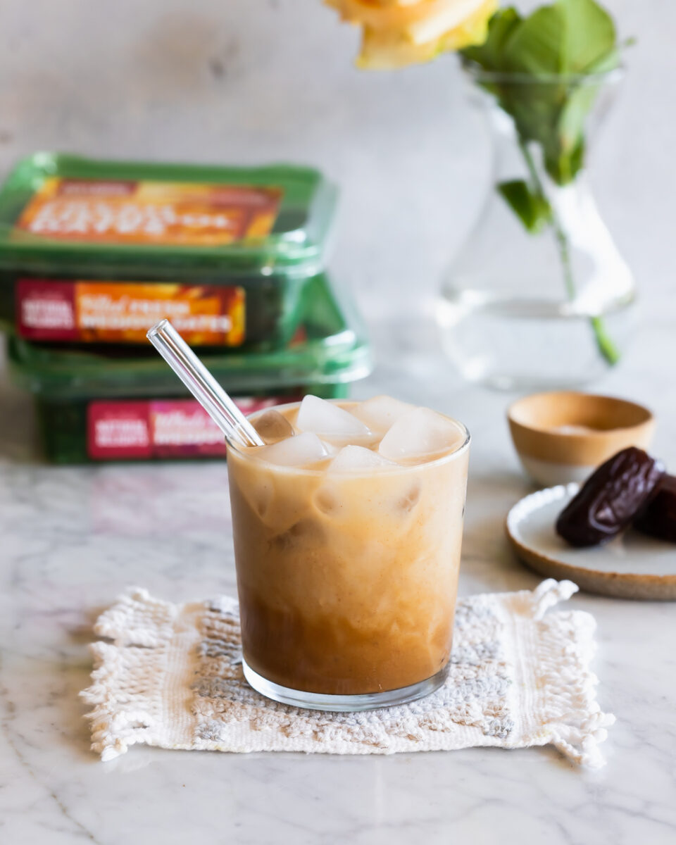 An iced caramel latte with packages of dates in the background